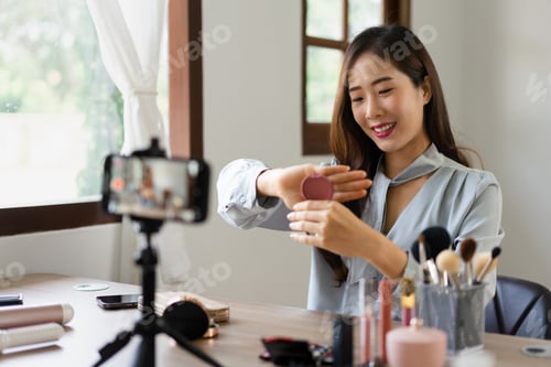 Preview: Beauty blogger holding blush on and showing product to reviewing cosmetic in makeup vlogger
