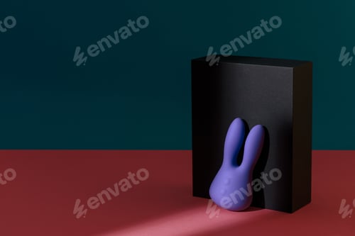 Preview: Violet dildo vibrator for clitoris with black gift box on colored background. Sex toy for