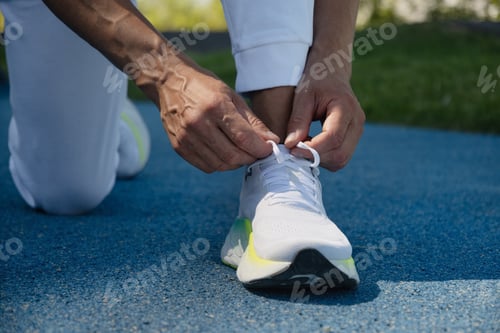 Preview: Athlete preparing work out. Man tying running shoes shoelace before jogging.