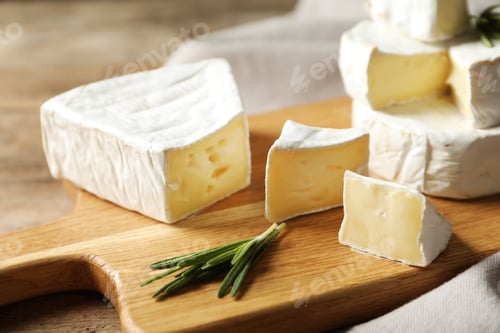 Preview: Wooden board with delicious cheeses on table, closeup
