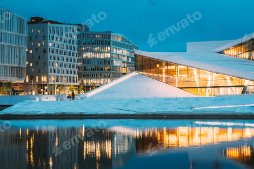 Preview: Oslo Norway. Evening View Of Illuminated Opera Ballet House Among High-Rise Buildings Under Blue Sky