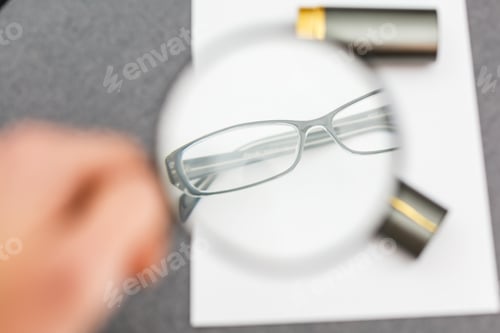 Preview: magnifier and glasses on a sheet of paper for business behind blind