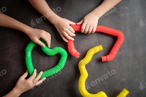 Preview: anti stress sensory pop tube toys in a kids hands. kids hands plays with poptube toy on black table