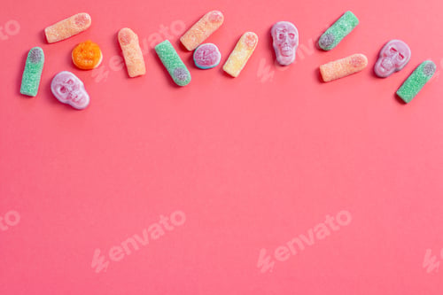 Preview: Halloween sweet background frame with scary pumpkin cookies, candy and Halloween decor on pink table