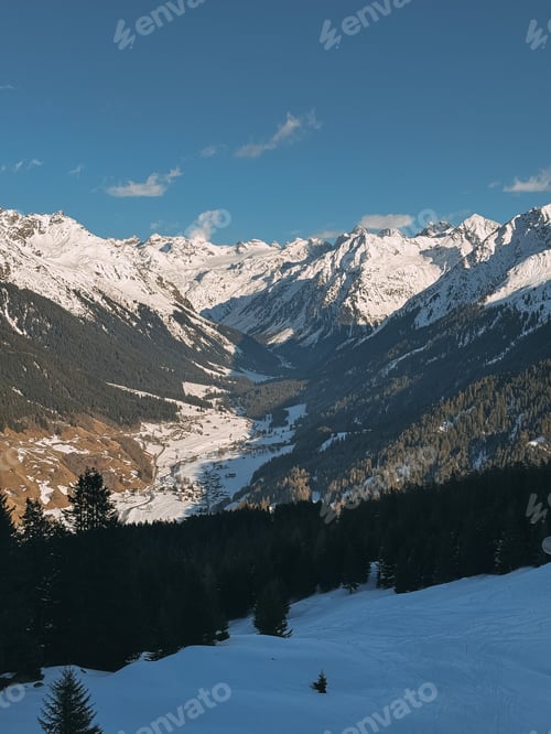 Preview: Snowy mountain peaks towering over a valley and pine forest kloster davos