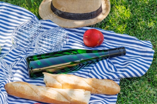 Preview: Picnic with wine, fruits, and baguette on a green meadow
