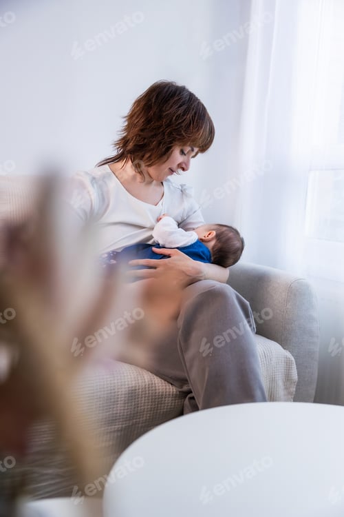 Preview: Mother breastfeeding newborn baby at home during daytime