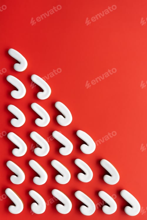Preview: A lot of gingerbread candy cane shaped cookies on a red background.