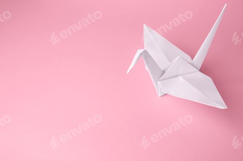 Preview: Origami art. Handmade paper crane on pink background, above view. Space for text