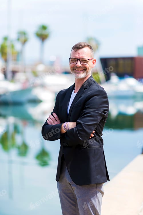 Preview: Mature businessman standing in the city arms crossed while looking camera and smiling
