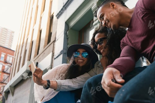 Preview: Three mid adult friends posing for smartphone selfie on city street