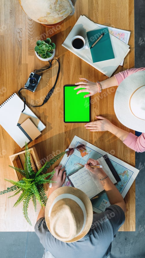 Preview: Top view of young couple with tablet planning vacation trip, desktop travel and green screen