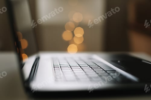 Preview: Close up of laptop keyboard with blank screen on a table by blurry bokeh lights background in the