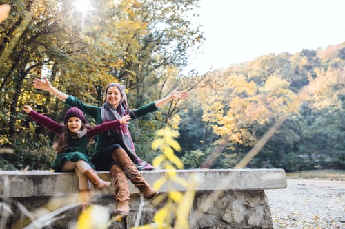 Vista previa: A mother with a toddler daughter sitting in forest in autumn nature, stretching arms