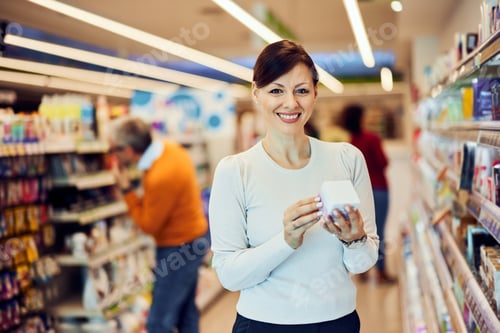 Preview: Portrait of a happy female customer holding a face cream in a white package.
