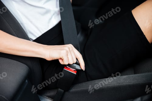 Preview: Woman sitting in car and putting on her seat belt