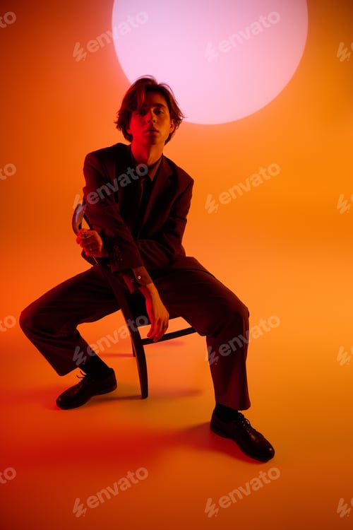 Preview: Stylish young man poses confidently in a vibrant setting with an artistic backdrop