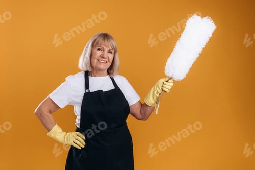 Preview: Ready to clean the house. Senior housewife is standing against background