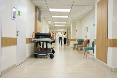 Preview: Dark-haired woman and middle-aged man walk along the hospital corridor