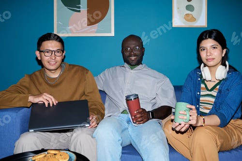 Preview: Multiethnic Adults Sitting on Couch Smiling and Holding Coffee Cups