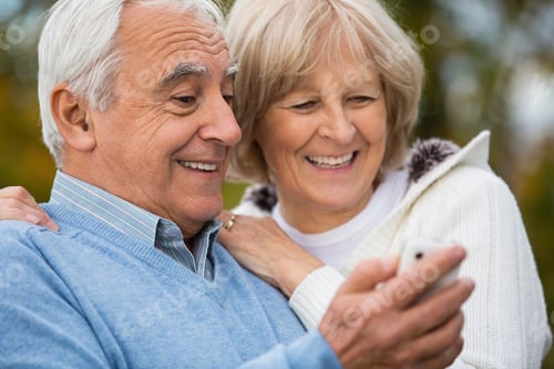 Preview: Portrait of smiling senior couple looking self-portrait at smartphone