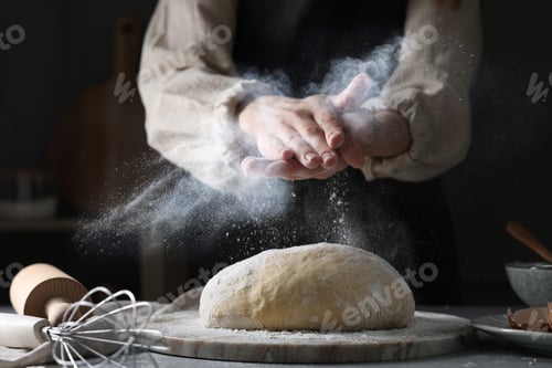 Preview: Woman dusting flour over dough at grey table, closeup