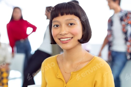 Preview: Front view of happy young Asian businesswoman looking at camera in a modern office