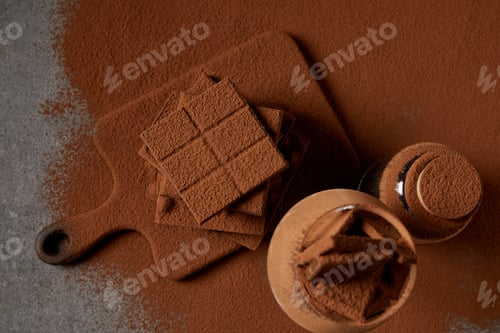 Preview: top view of tasty chocolate pieces with cocoa powder on chopping board