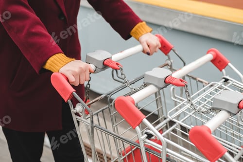 Preview: Unrecognizable person in aburgundy coat and yellow sweater walks on the roof of supermarket parking