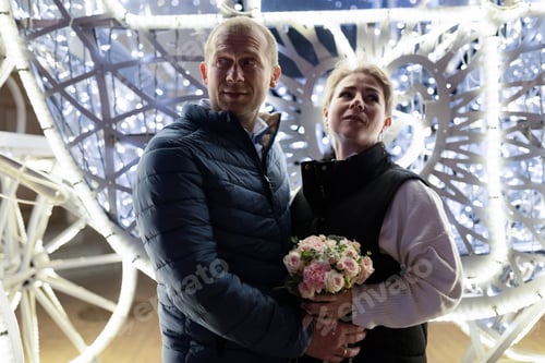 Preview: A couple walks through the city at night, illuminated by festive lights