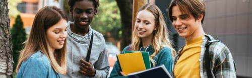 Preview: Horizontal crop of smiling multiethnic teenagers with notebooks sanding near tree outdoors