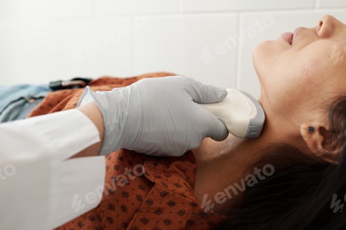 Preview: Gloved hand of doctor holding ultrasound scan on neck of patient