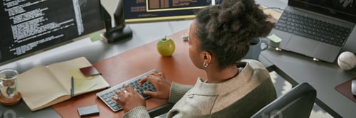 Preview: Header Image of Black Woman Coding Software at Desk in Office Workspace