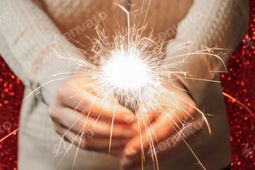 Preview: New Year celebration. Young woman holds sparkler in her hands. Christmas night. Bright sparks