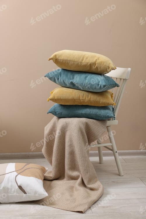 Preview: Soft pillows and warm blanket near beige wall indoors