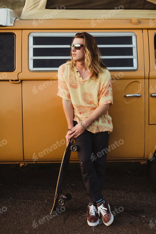 Preview: Young male skateboarder leaning against vintage recreational vehicle, Exeter, California, USA