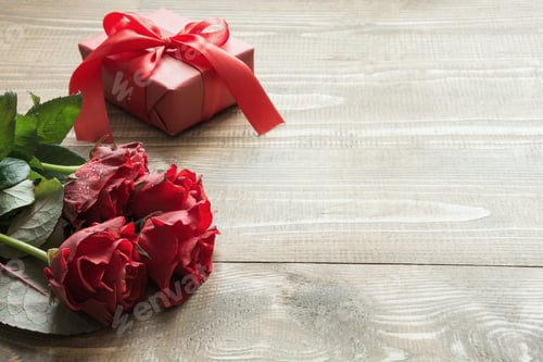 Preview: Bouquet red rose flowers and gift box on wooden table. Copy space. Close up.
