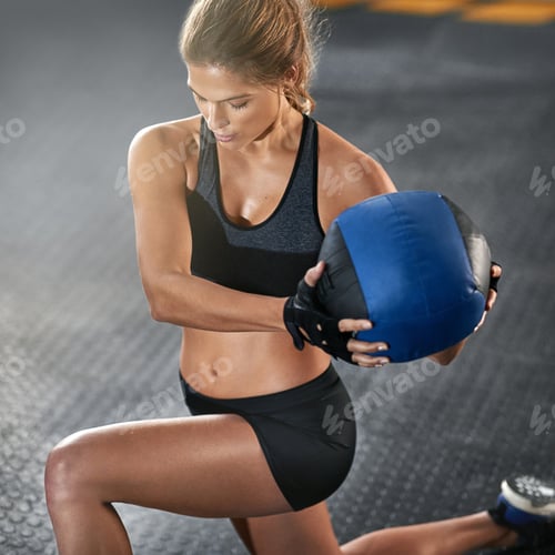 Preview: Go hard or go home. Cropped shot of a young woman working out with a medicine ball at the gym.