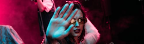 Preview: panoramic shot of girl in sunglasses showing hand at camera in nightclub during rave party