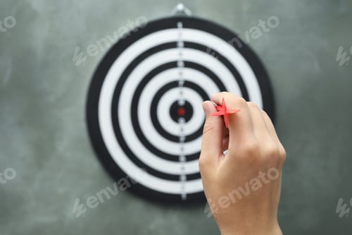 Preview: Woman throwing red arrow at dart board on grey background, closeup