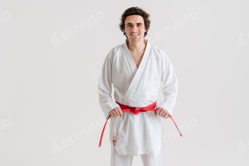 Preview: Young caucasian sportsman dressed in kimono holding his belt