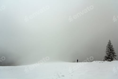 Preview: Far away lonely figure of a man standing outdoors in winter