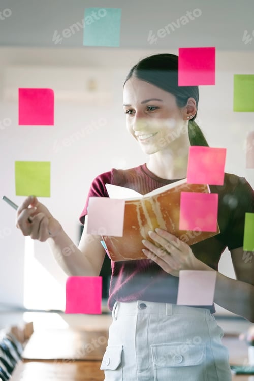 Preview: businesswoman using post it notes in glass wall to writing strategy business plan.
