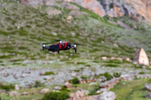 Preview: Modern dark and red drone in the air in mountains close