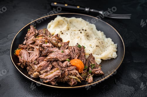 Preview: Beef stew with mashed potatoes, carrots and herbs on a plate isolated. black background. top view