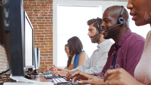 Preview: Multi-Cultural Business Team Wearing Headsets Working In Busy Customer Service Department