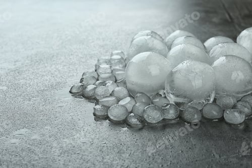 Preview: Many melting ice balls on dark grey table, space for text