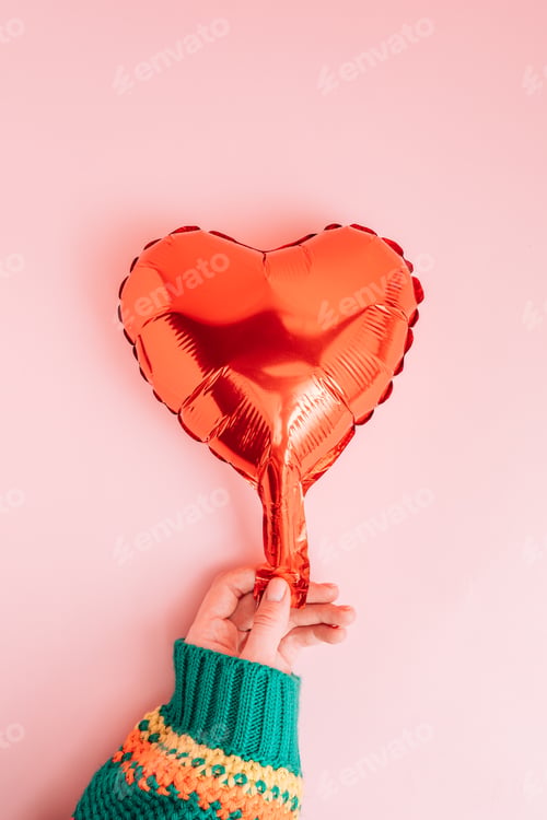 Preview: Red balloon in a woman's hand against a pink background
