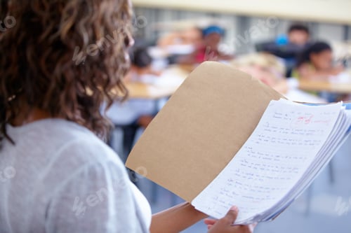 Preview: Ready to announce the marks. An over the shoulder view of a teacher reading out student marks.