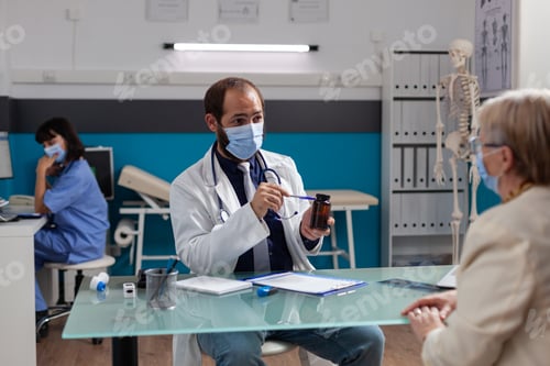 Preview: Health specialist giving bottle of pills to retired woman at checkup visit
